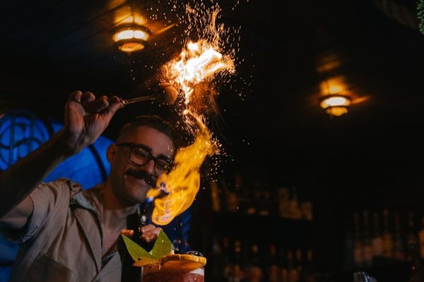 A bartender lights up a Shattered Skull cocktail at the Sunken Harbor Club.