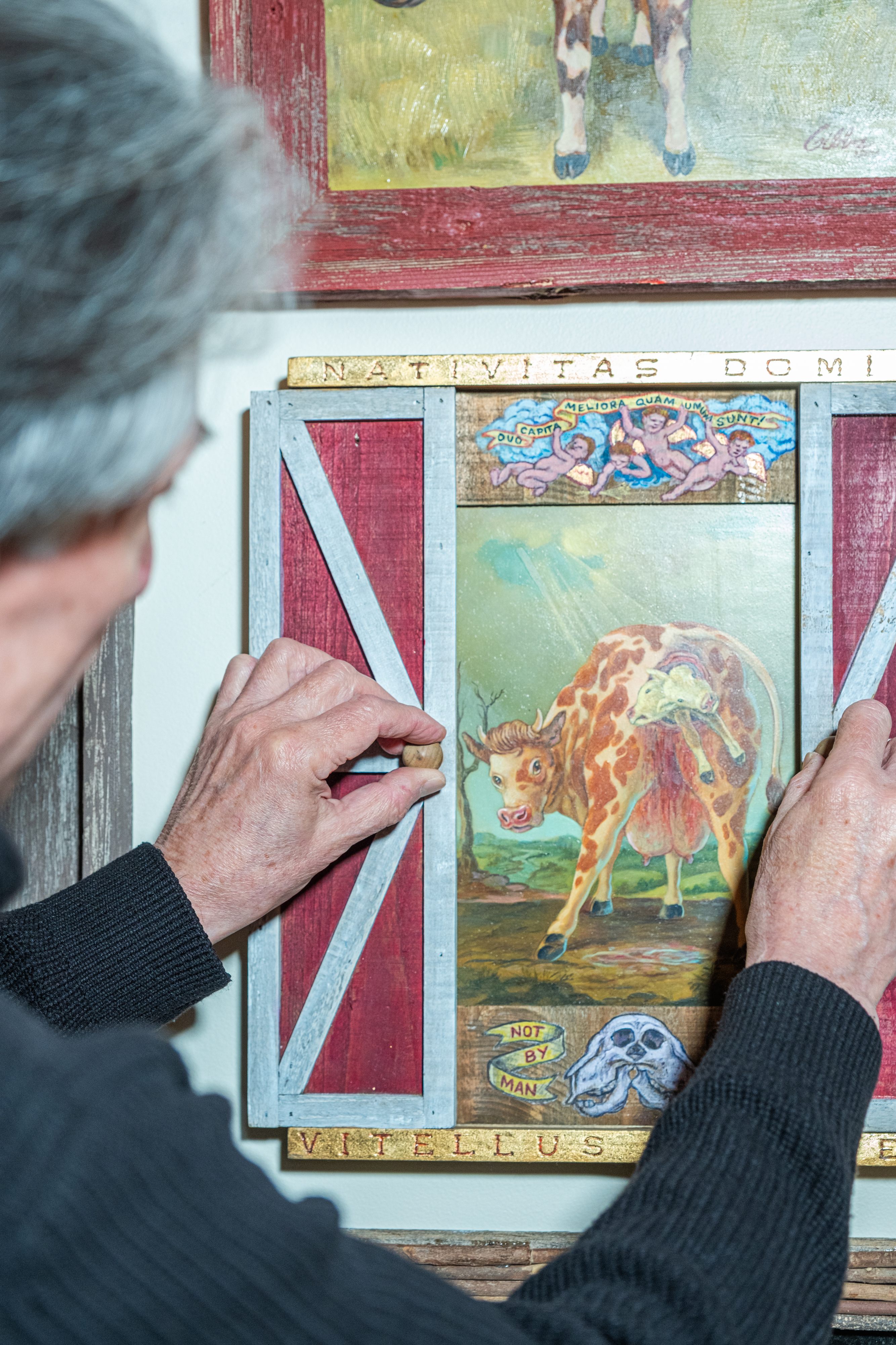 Rosenthal slides open a set of miniature barn doors to reveal a painting of a cow giving birth to a two-headed calf.